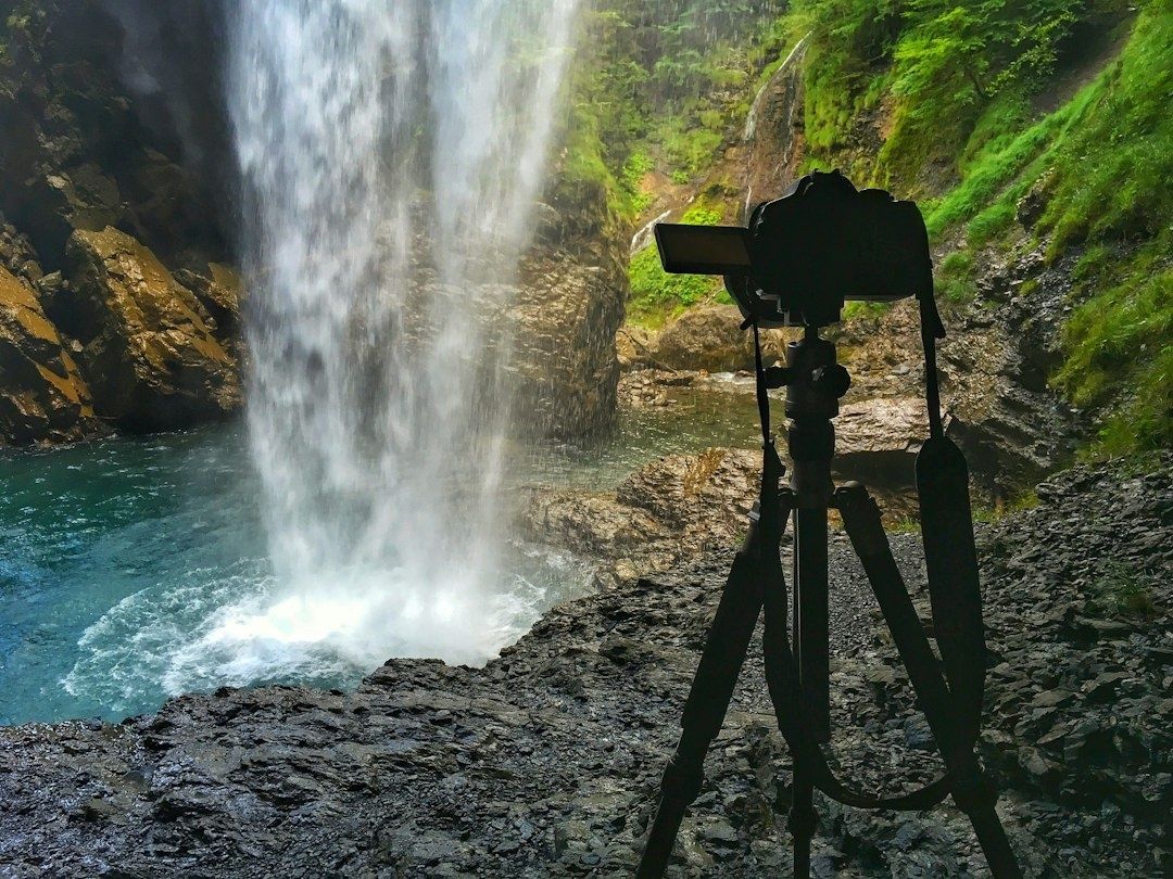 Kamera auf Stativ vor einem Wasserfall mit türkisfarbenem Becken
